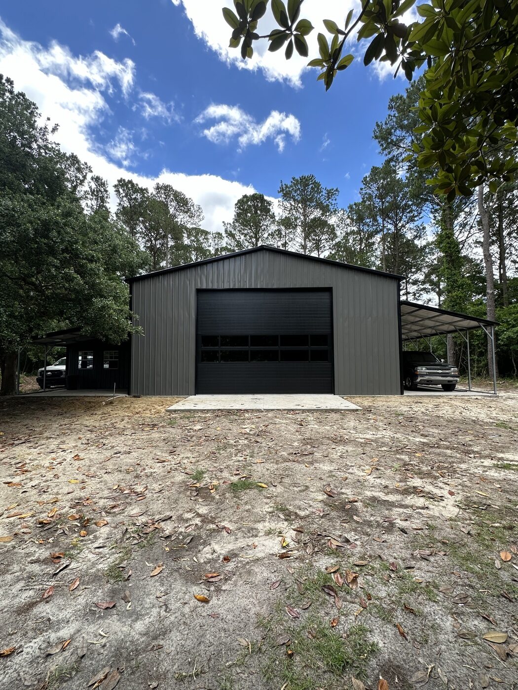 Gray detached metal building with overhead garage door